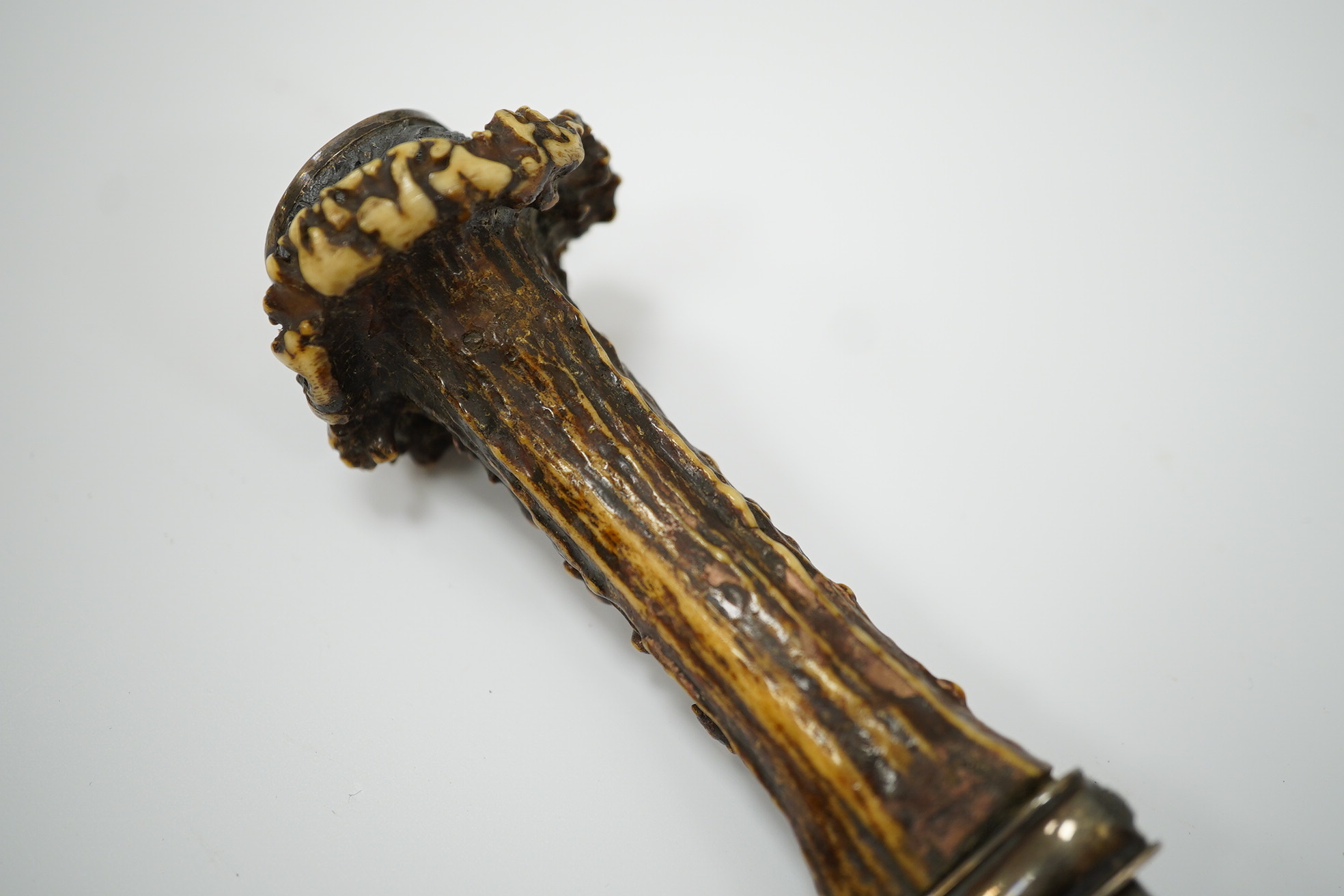 A late 19th century Scottish traditional sgian dubh with foiled glass mounted deer antler handle, and silver coloured metal mounts with thistles in relief, blade 10cm. Condition - fair, missing chape.